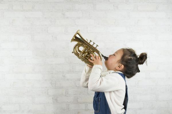 Image of child blowing into toy trumpet. 