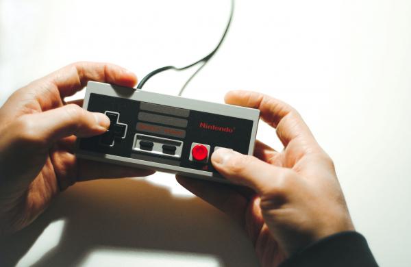 Person holding a video game controller/Persona sosteniendo un control de videojuego