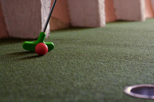 a green putter hits a red golf ball. fairy golf will be much smaller than what is pictured.