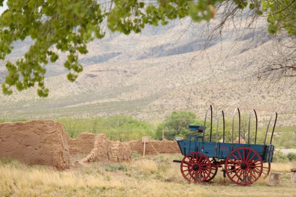 a blue and red mail wagon in front of sandy ruins