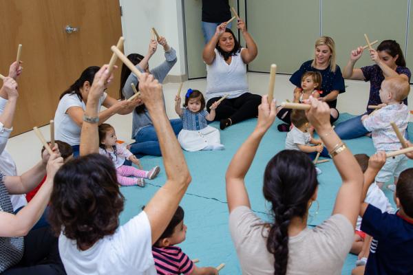 Image of parents and children tapping rhythm sticks