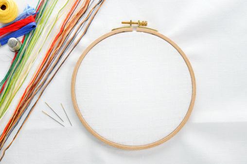 Image of an embroidery hoop with thread and needles off to the side