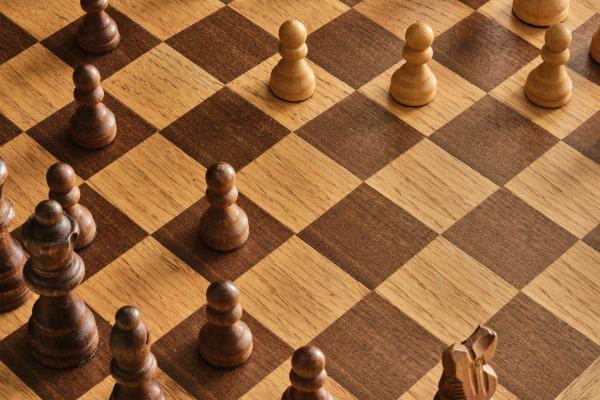 An image of a wooden chessboard, with pawns moving towards the center.