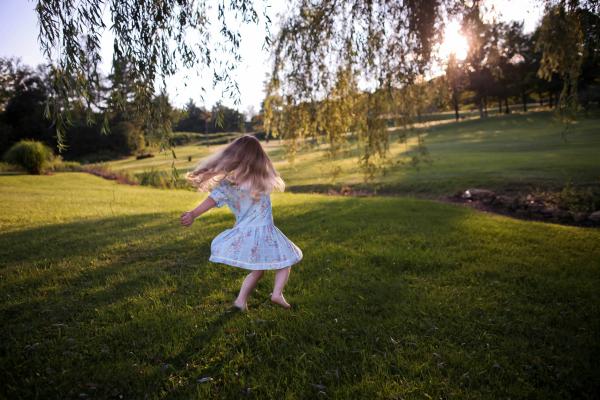 Girl in dress spinning around on grass