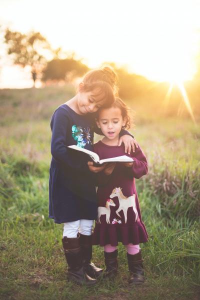 Two girls reading in the middle of a field