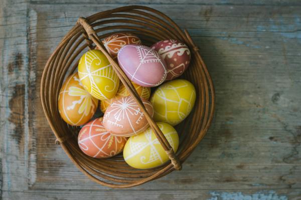 A wicker basket full of brightly colored Pysanky style eggs