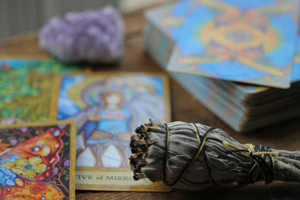Tarot cards on a table with a sage bundle and cards.