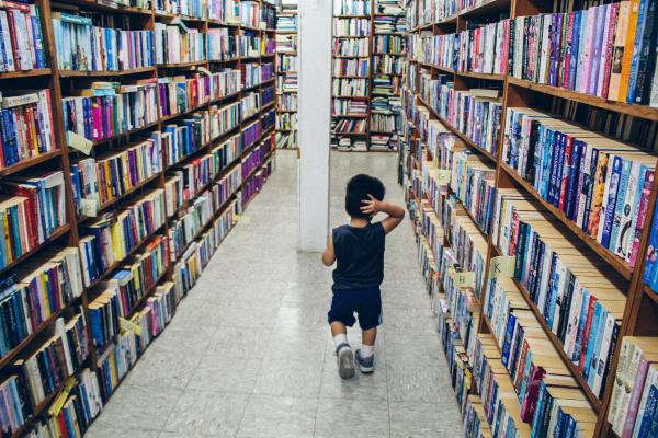 Small child walks through stuffed bookshelves.