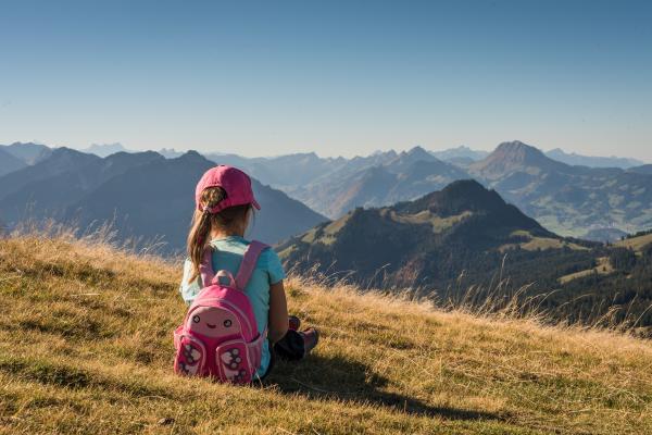 Child sitting in the grass looking at a mountain view.