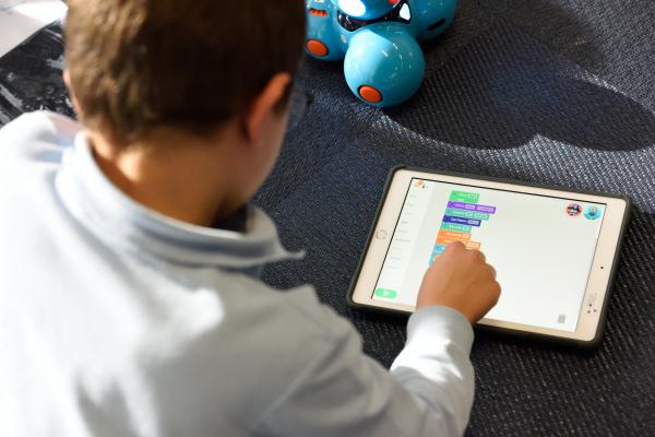 Child using a tablet to code a robot.