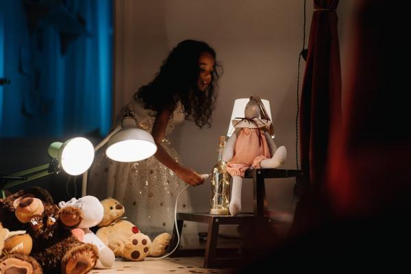 Girl playing with stuffed animals and lamps.