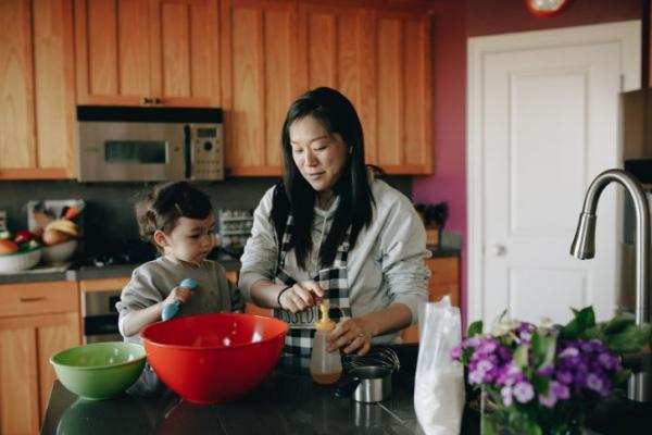 Caregiver and child cooking in a kitchen.