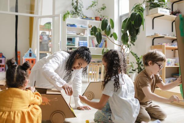 Four children creating something together inside using cardboard.