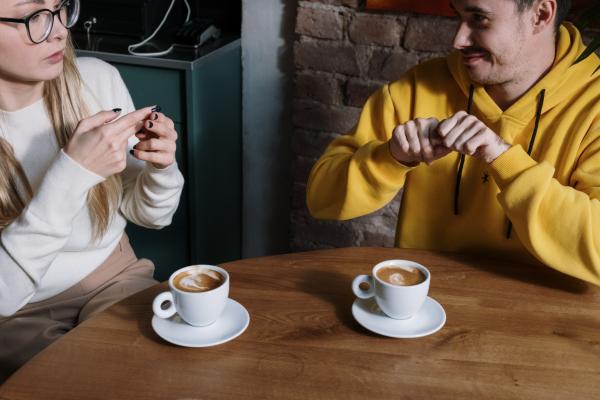 Two people having a conversation using ASL over coffee