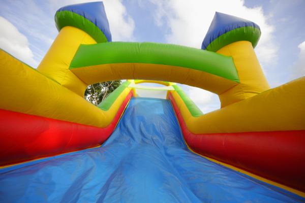 a multicolored inflatable castle with slide against a blue and white sky