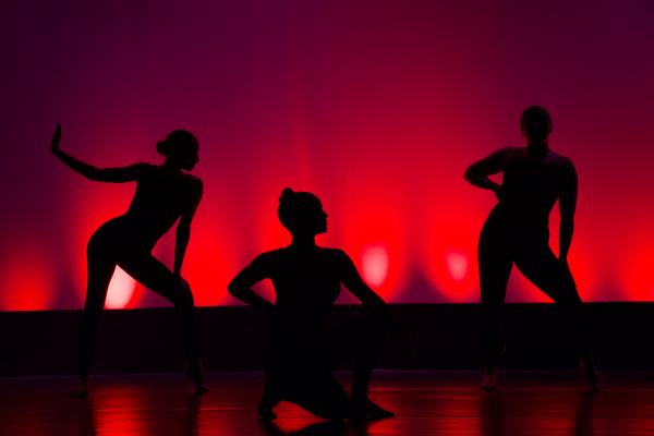 Silhouettes of three dancers against a red background