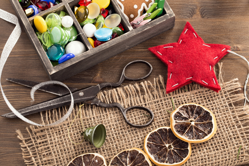 Scissors, a box of buttons, and other craft supplies laid out on a wooden table