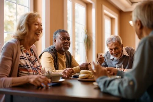 Four senior citizens laughing around a table