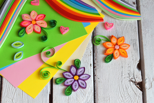 Brightly colored paper flowers laid out on a wooden floor