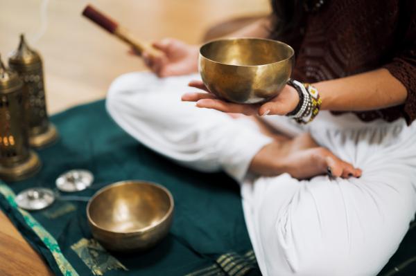 Person sitting cross-legged and holding a singing bowl