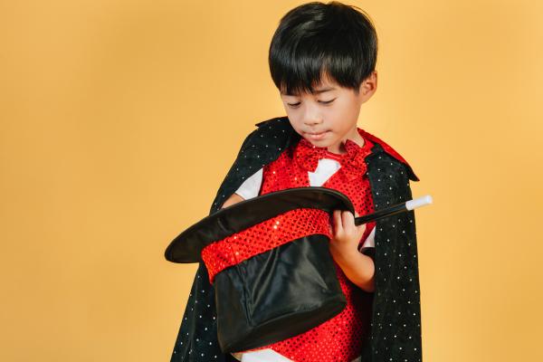 Child dressed as magician putting hand in hat