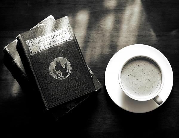 black-and-white photograph of Longfellow poem book and cup of coffee