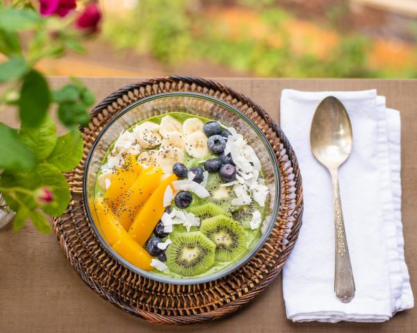 bowl of kiwi, mango, banana, blueberries on outdoor table