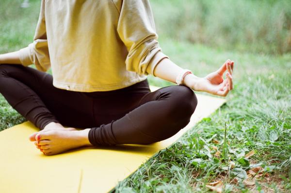 Woman on yellow yoga mat, meditating in nature