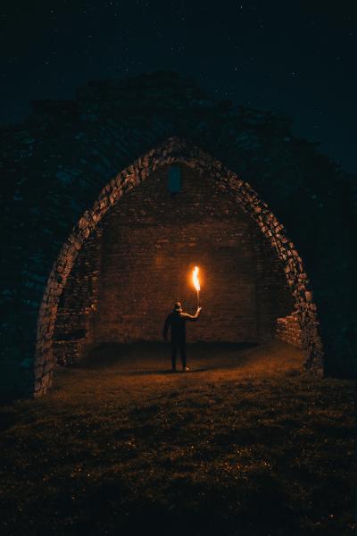 An image of an adventurer with a torch in a crypt.
