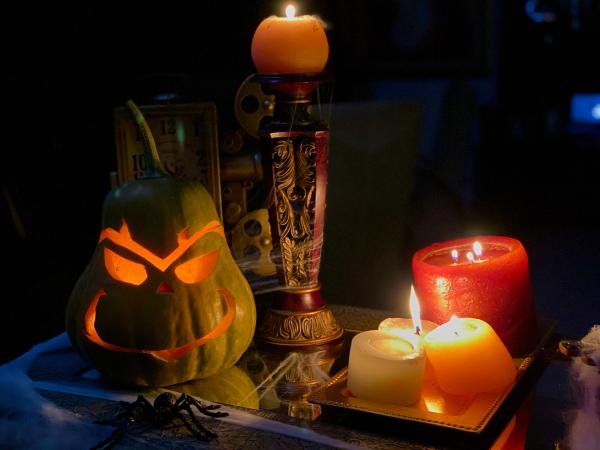 a jack-o-lantern next to burning candles