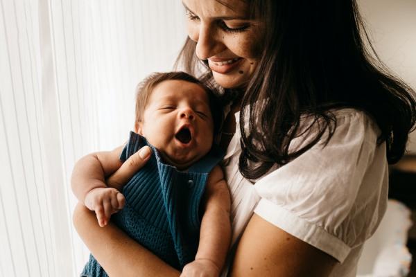 Caregiver holding yawning baby.