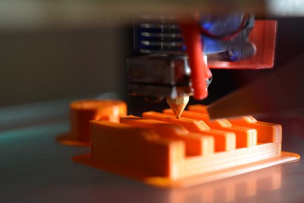 A 3D printer printing an orange model.