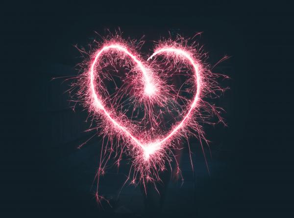 A heart made of pink sparks on a black background