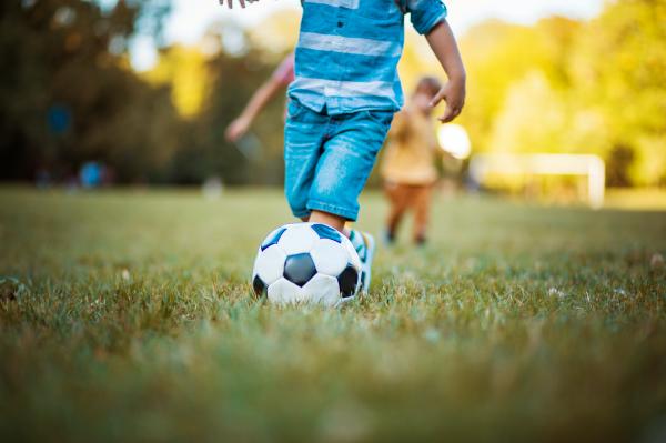 Children kicking a soccer ball outside.