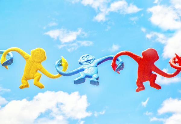Three colorful barrel of monkeys attached in front of a cloudy sky.