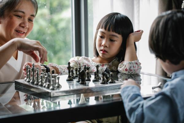Two children and a woman playing chess
